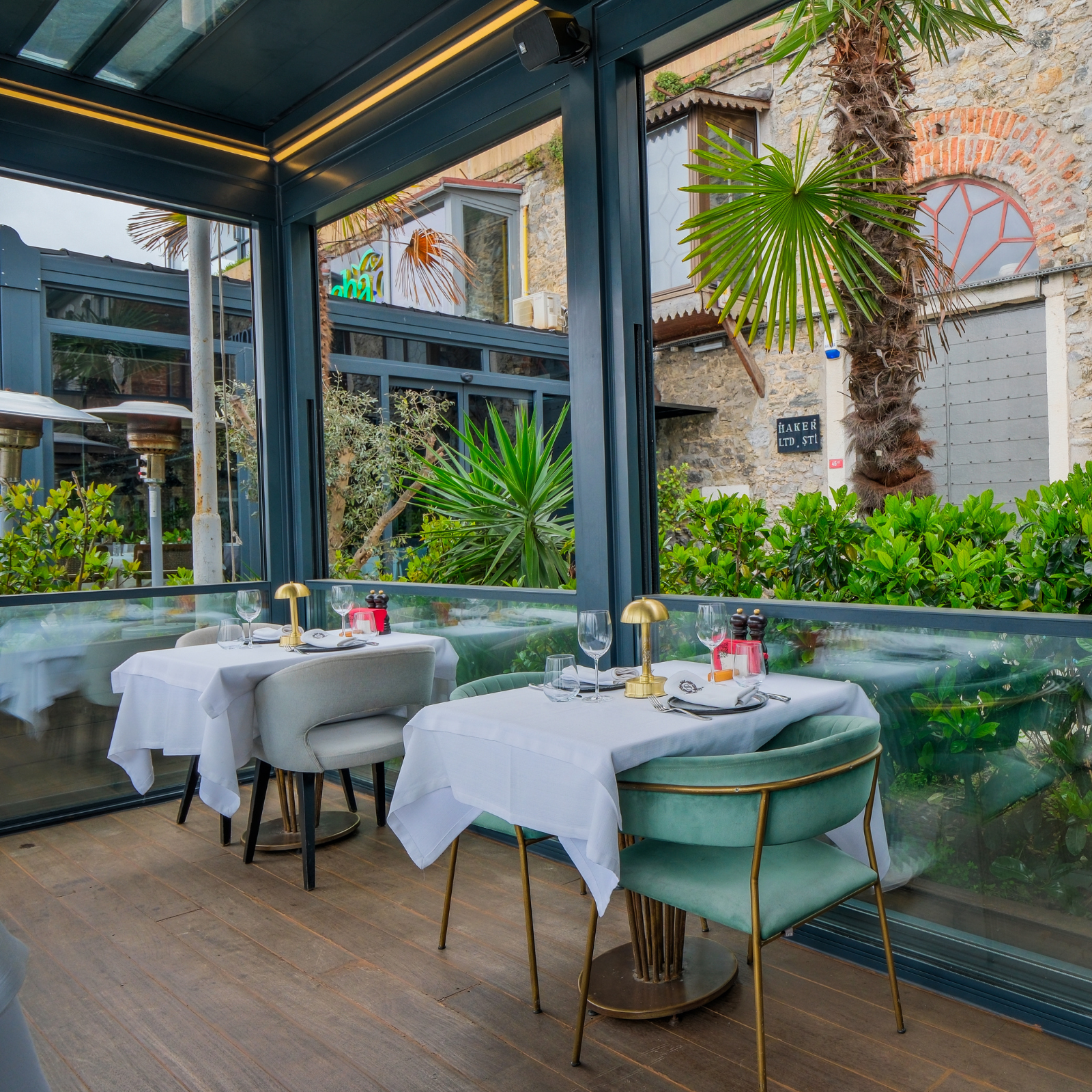 Elegant restaurant patio enclosed with an aluminum pergola and guillotine glass system by AnkaSpaces, providing a refined and weather-protected outdoor dining space.