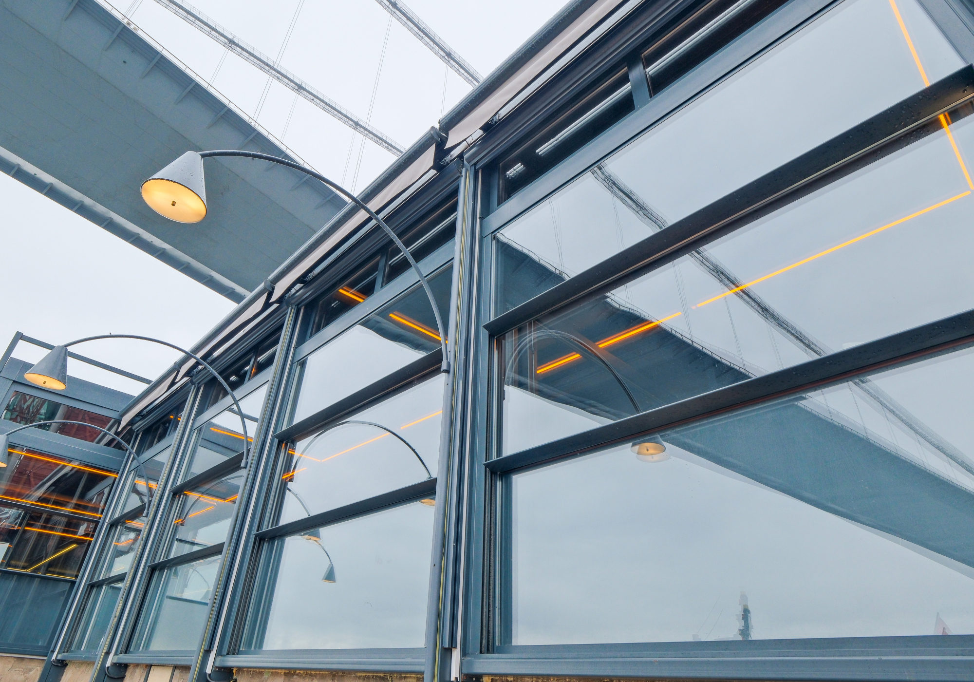 Motorized guillotine glass system by AnkaSpaces, featuring vertical sliding panels and integrated lighting for weather protection and modern design